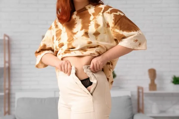 Image of woman trying to do her trousers up after pregnancy weight gain Hadleigh