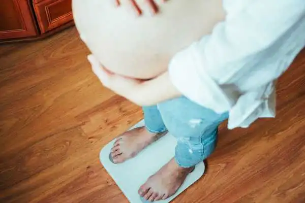 Image of woman weighing herself and experiencing weight gain through pregnancy Hadleigh